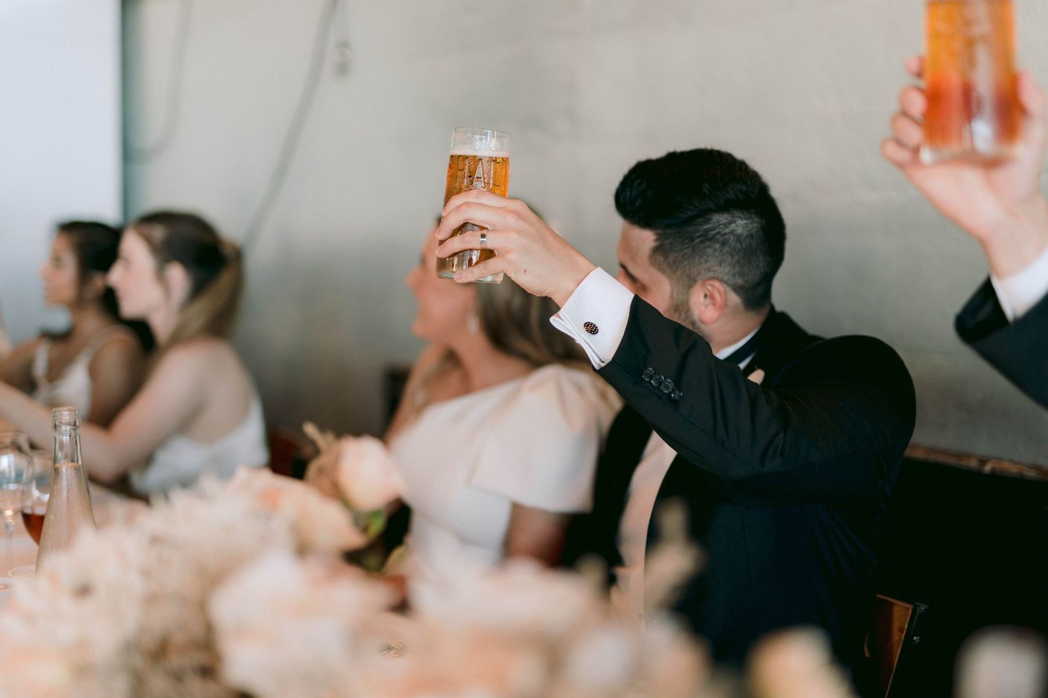 Person in formal attire raises a champagne toast at an elegant wedding reception.