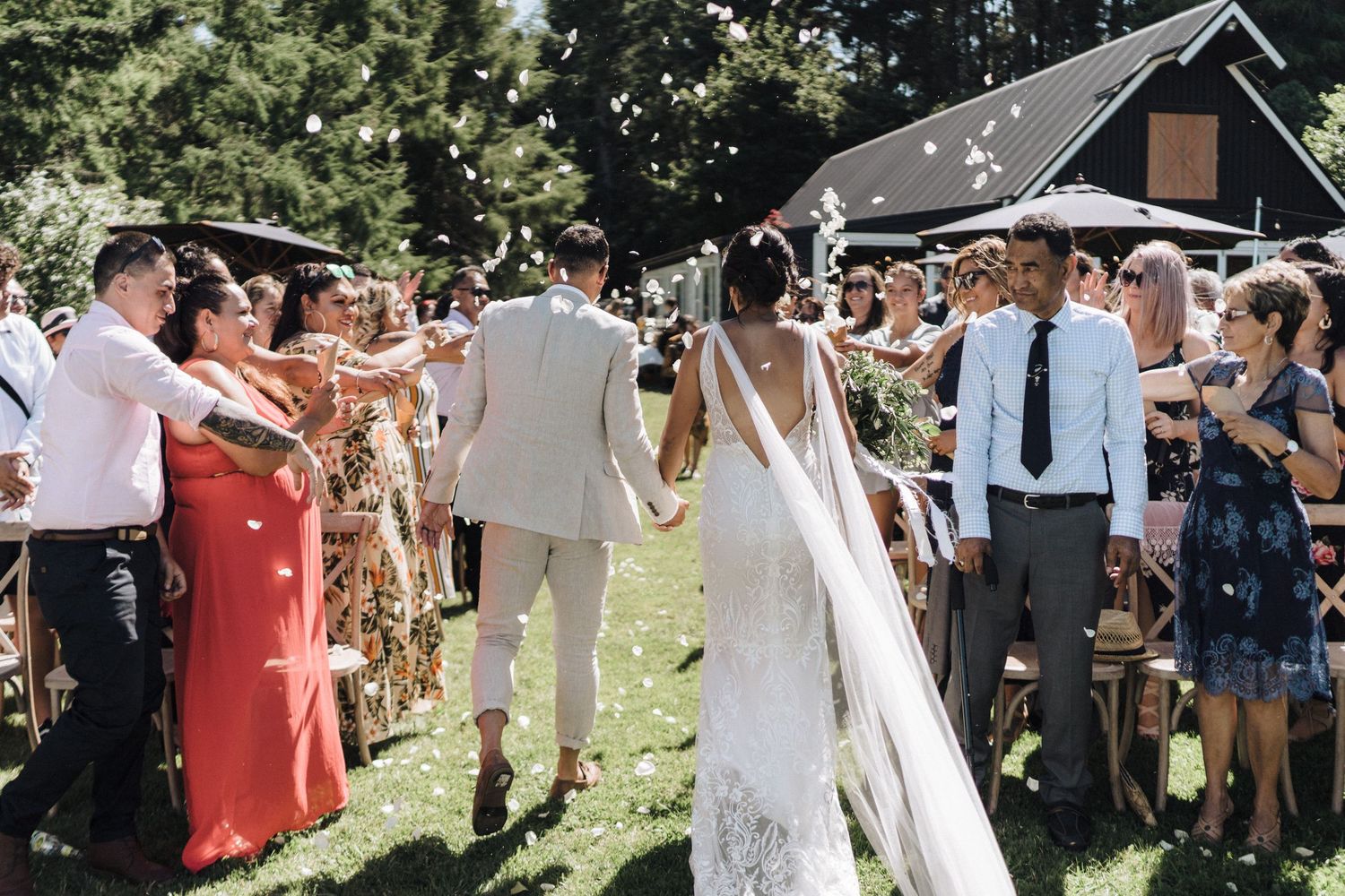Wedding guests blow bubbles as the newlyweds walk through a garden during their outdoor celebration.