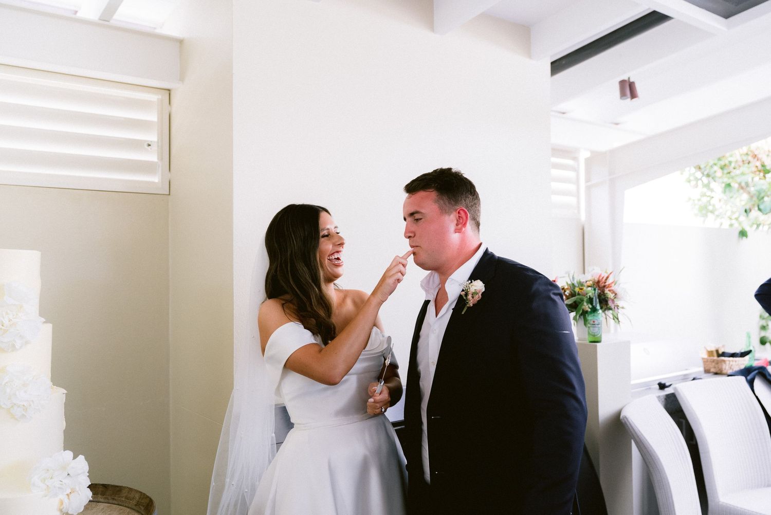 Wedding party members sharing joyful moments in a bright indoor venue with white decor.