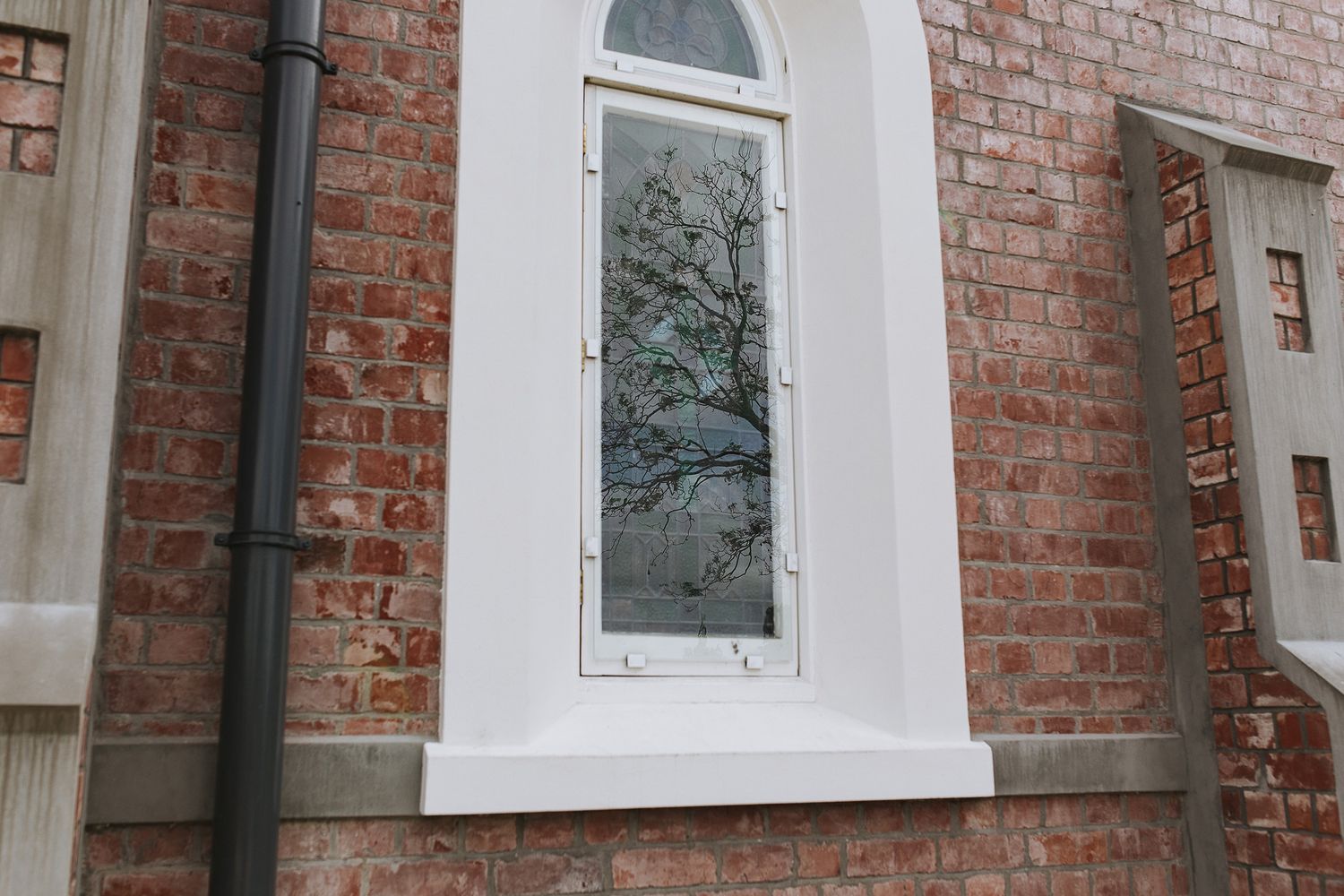 Decorative white framed windows adorn the facade of a historic brick building with arched architectural details.