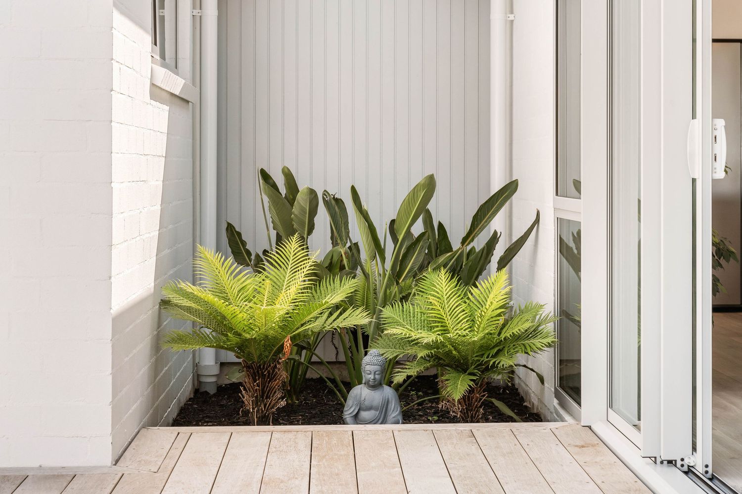 Interior hallway with vertical blinds and tropical plants creating a bright, airy atmosphere.