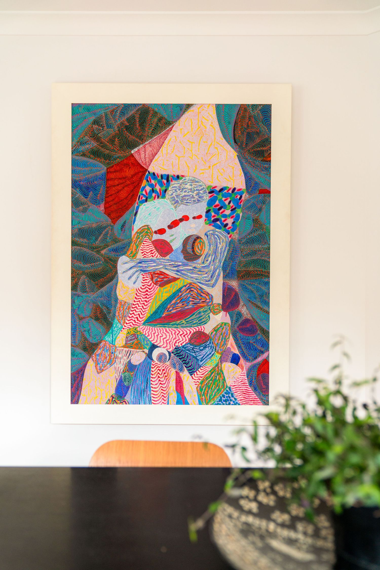 Colorful abstract art piece featuring geometric patterns and shapes in vibrant blues, reds and pinks against a beige background.