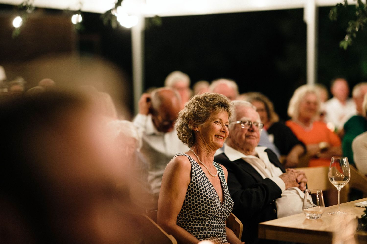Wedding guests enjoy entertainment at an outdoor evening reception.