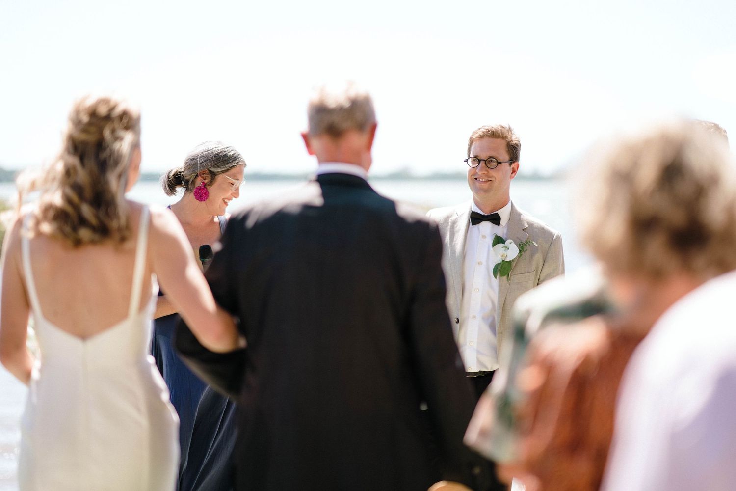 Wedding guests mingling at an outdoor reception overlooking a waterfront view.