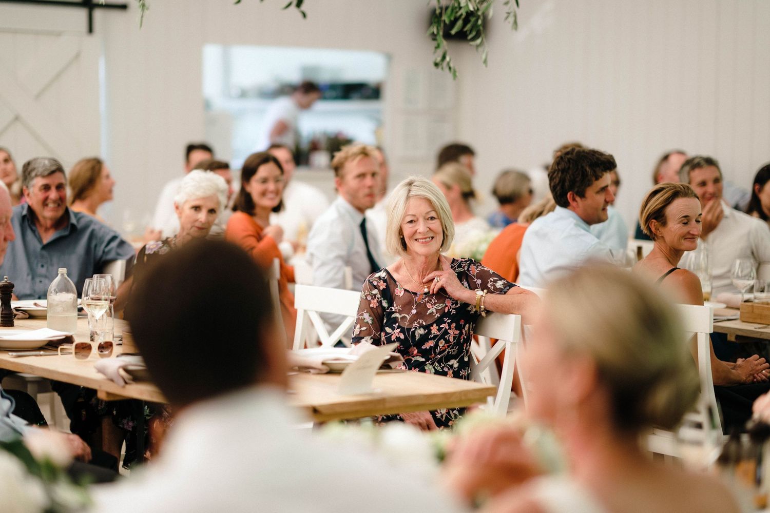 Reception guests enjoying conversation and laughter at wedding dinner tables.