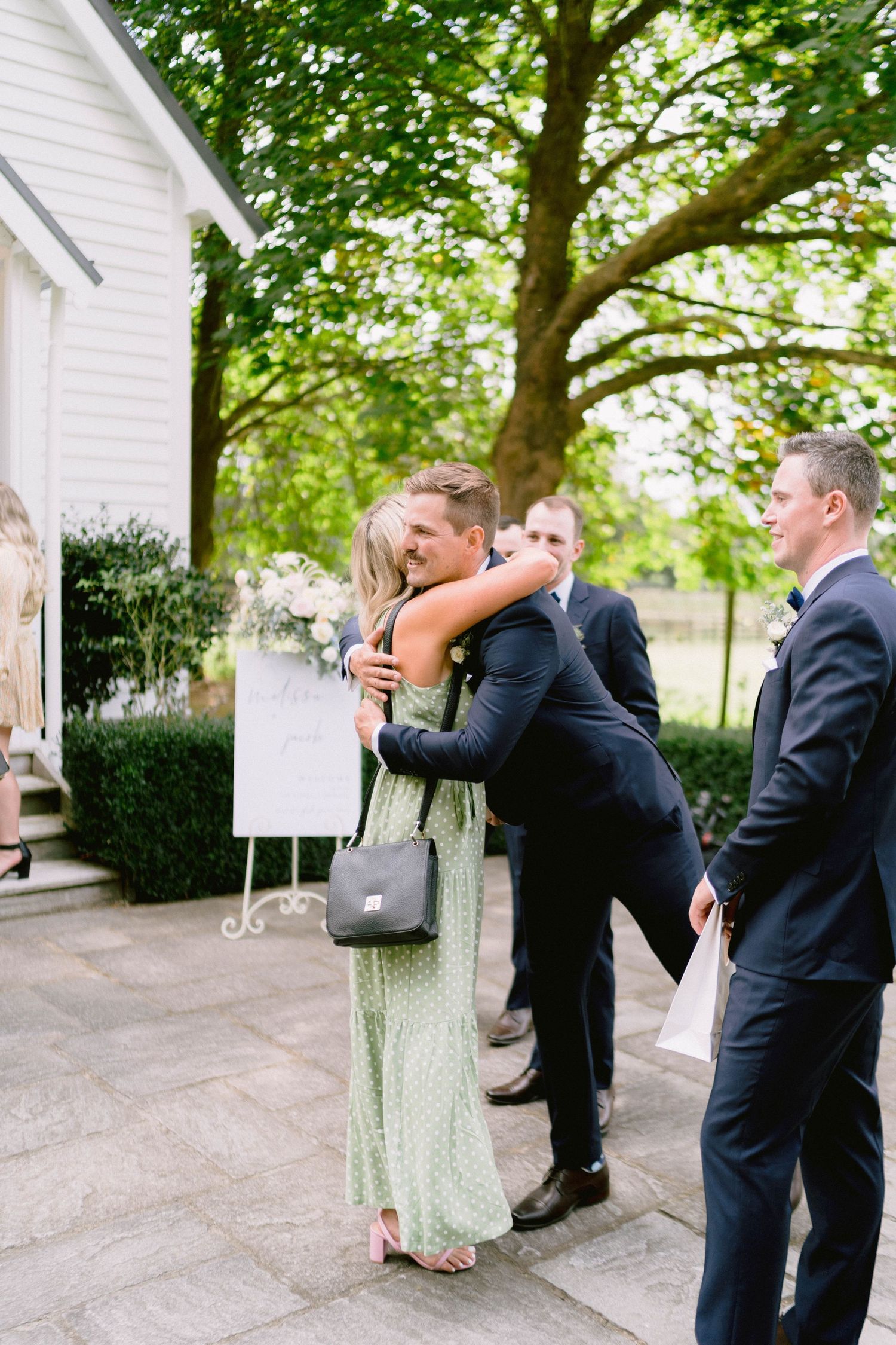 A romantic outdoor wedding moment between a couple in formal attire near white garden structures.