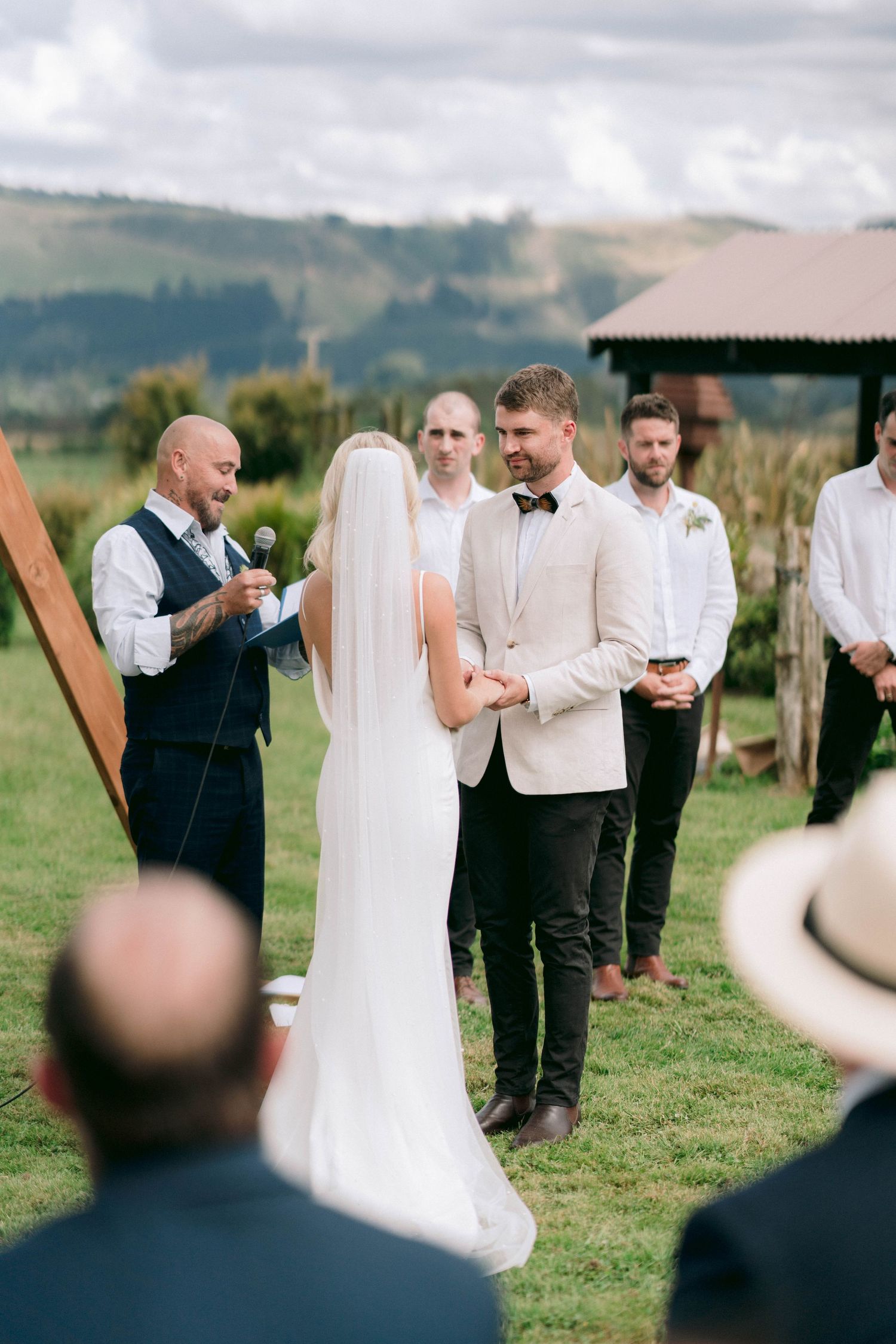 An outdoor wedding ceremony taking place on a scenic hillside with guests watching.