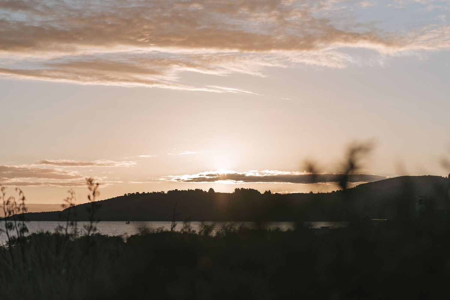 Sunset sky with golden clouds over silhouetted mountains and trees creates a dramatic panoramic landscape view.