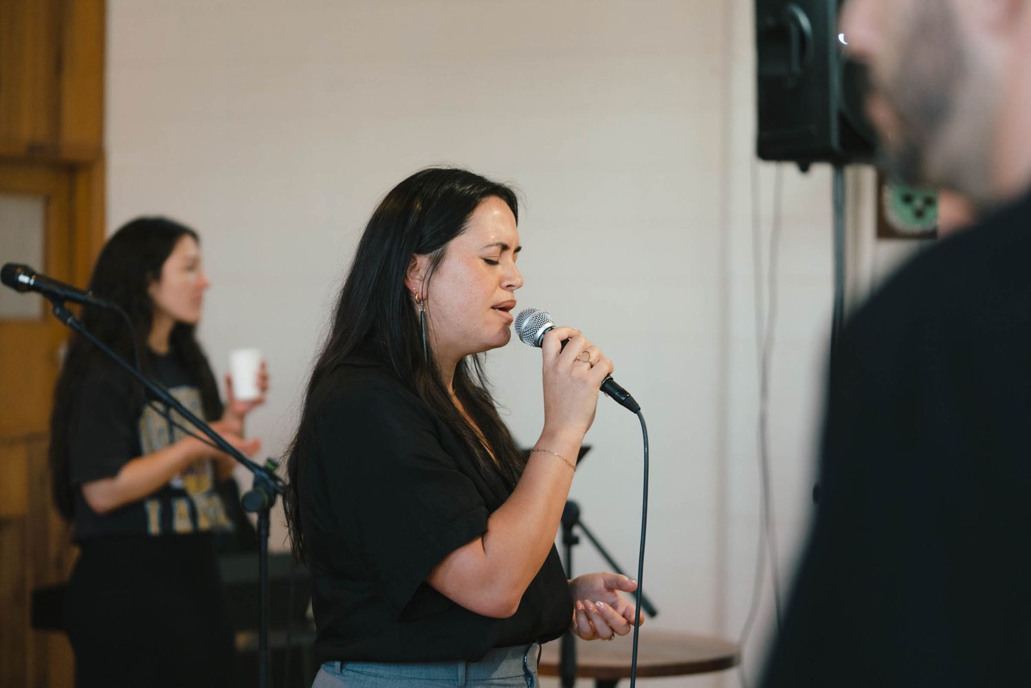 A singer performing with a microphone in a church worship setting.