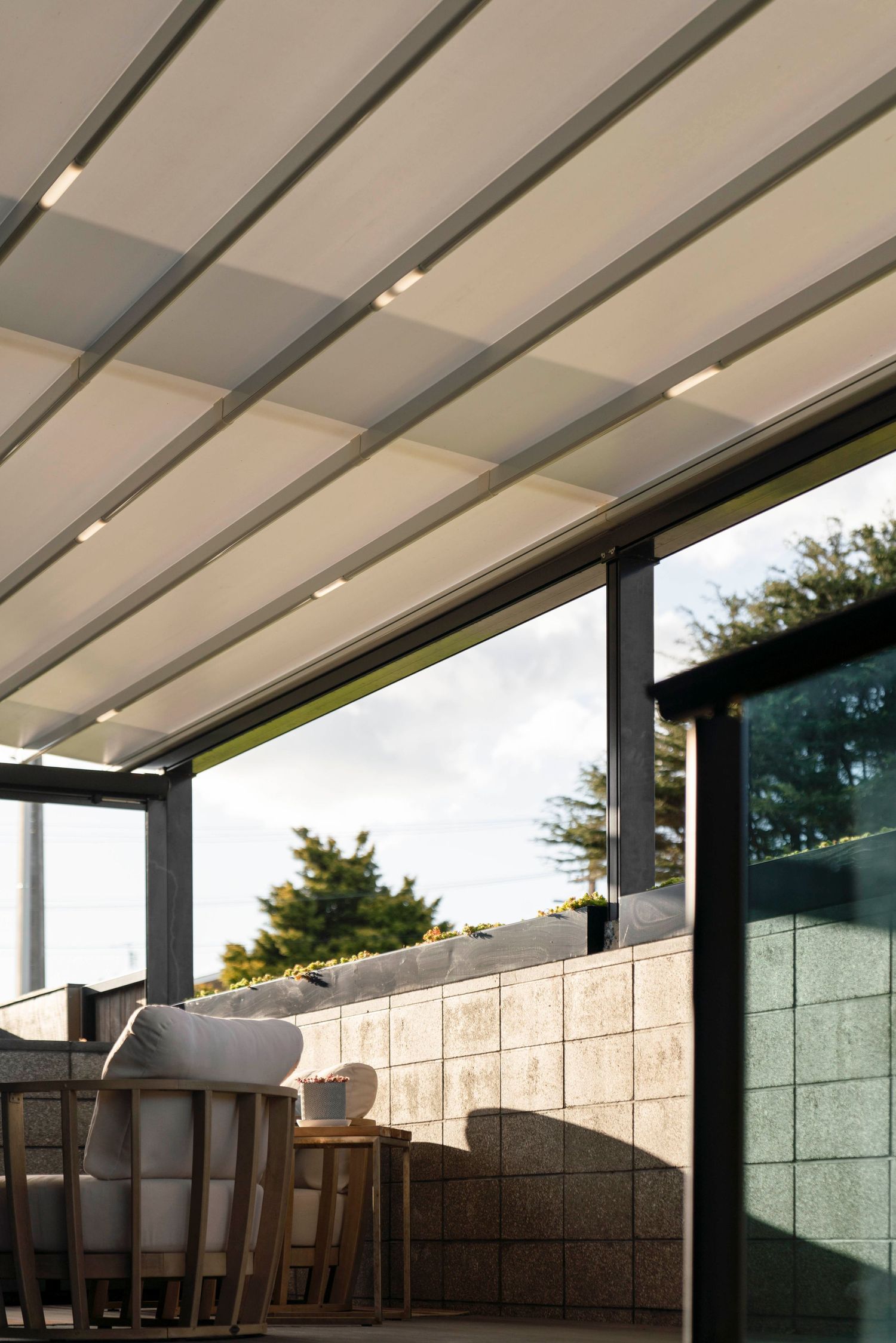 Modern retractable awning with LED lighting installed over an outdoor patio seating area.