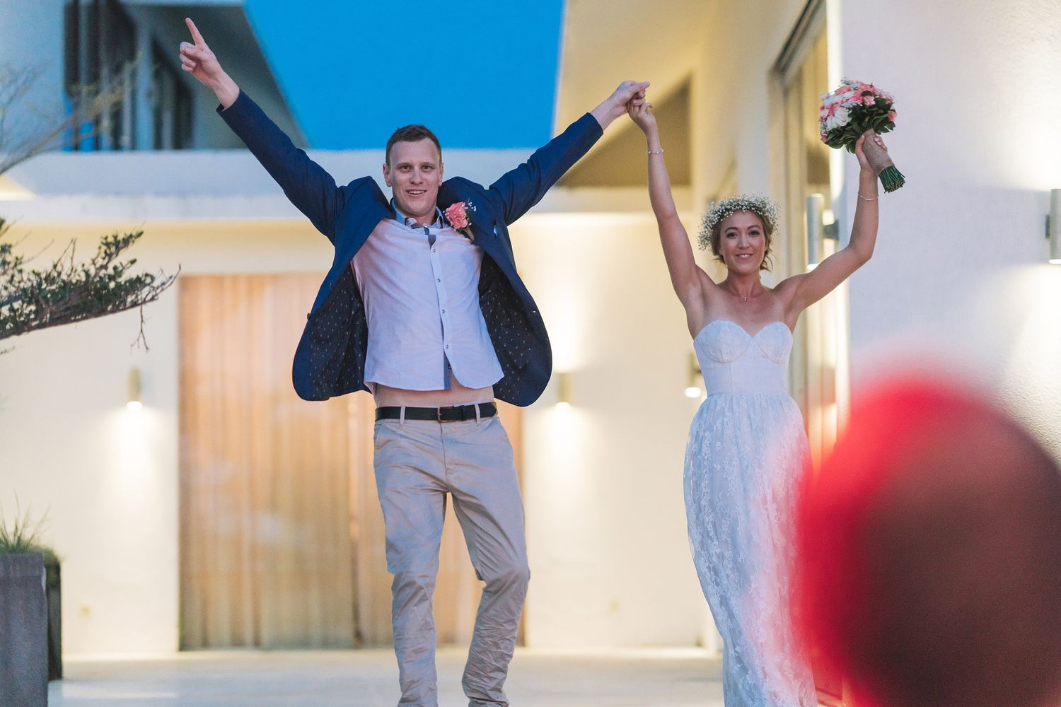 Wedding guests celebrating with arms raised during an indoor reception.