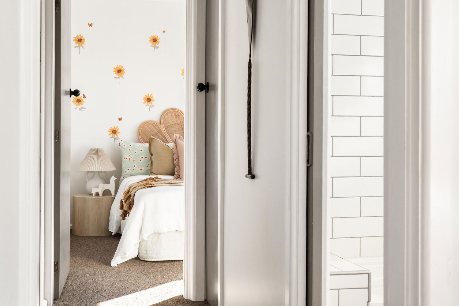 Peek through doorway into a cozy bedroom with floral wall decals and neutral decor.