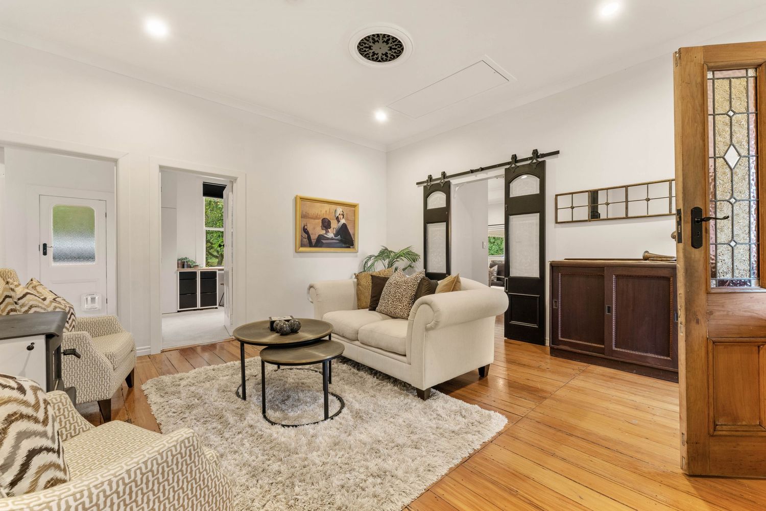 Contemporary living room with hardwood floors, beige sofa, and elegant vintage wood accents.
