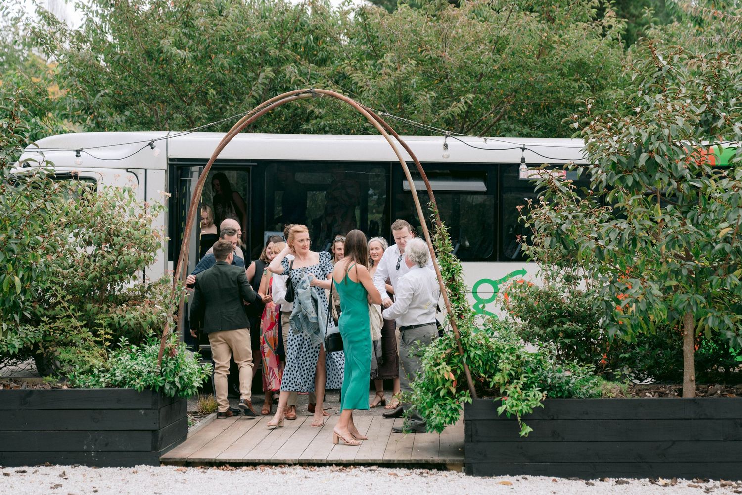 Outdoor wedding venue with string lights and wooden decor in a garden setting.