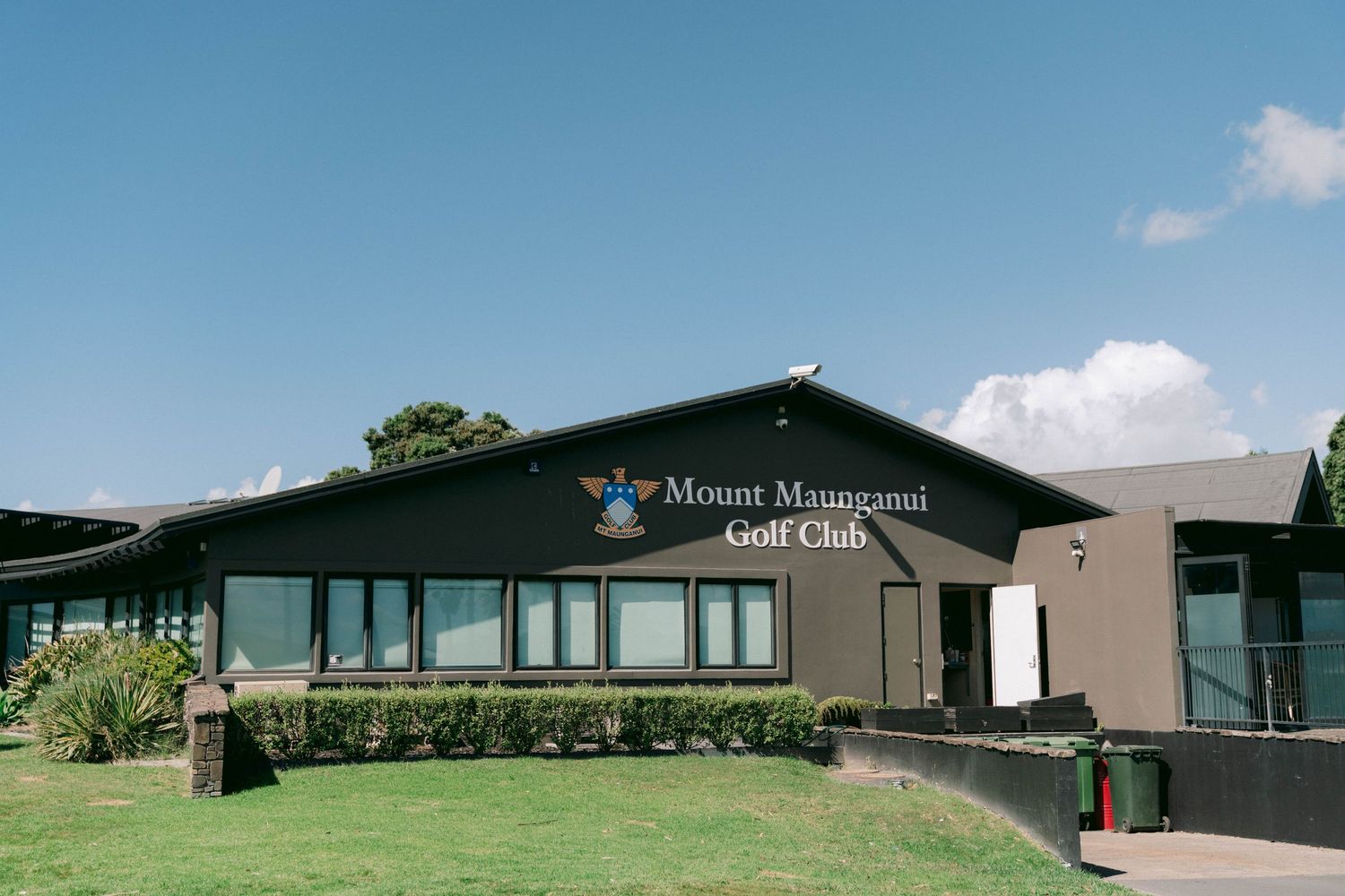 Mount Maunganui Golf Club building exterior with green grass and blue sky.