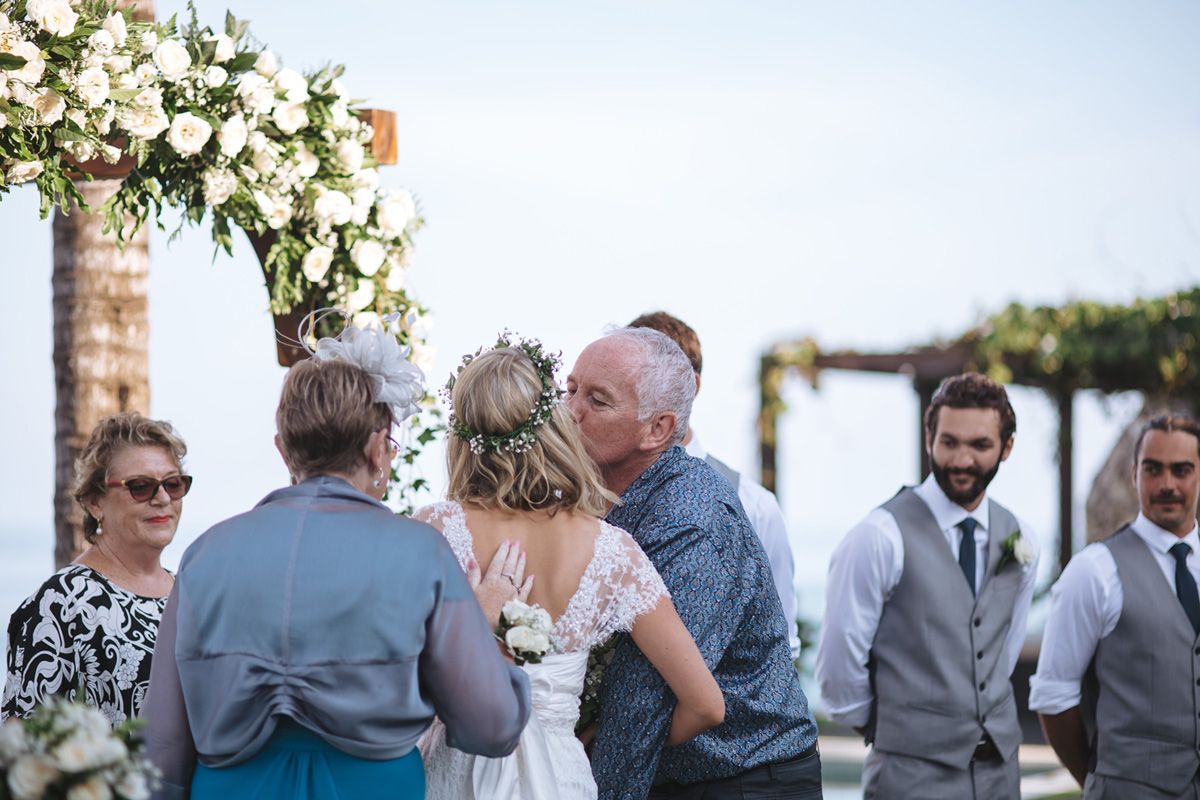 Wedding guests mingle during outdoor reception with decorative floral arrangements.