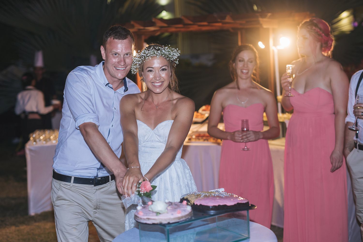 Wedding celebration at night with pink bridesmaid dresses and outdoor lighting.