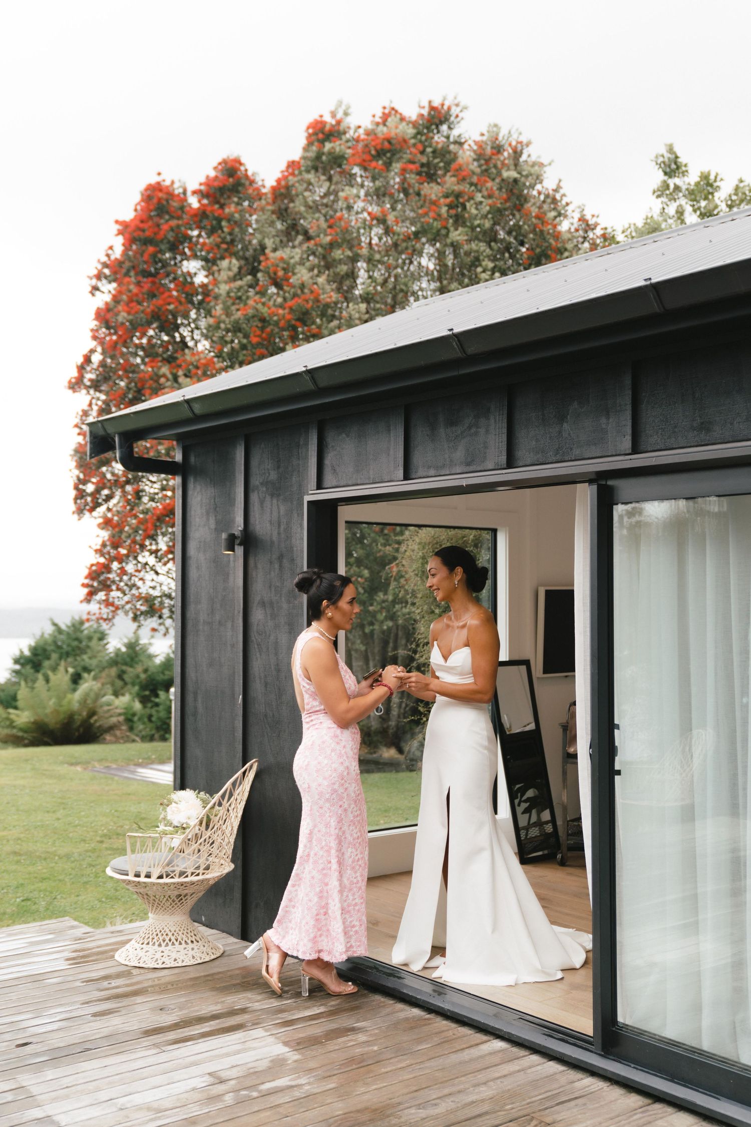 Two people share a moment on a deck outside a modern cabin with autumn trees in the background.