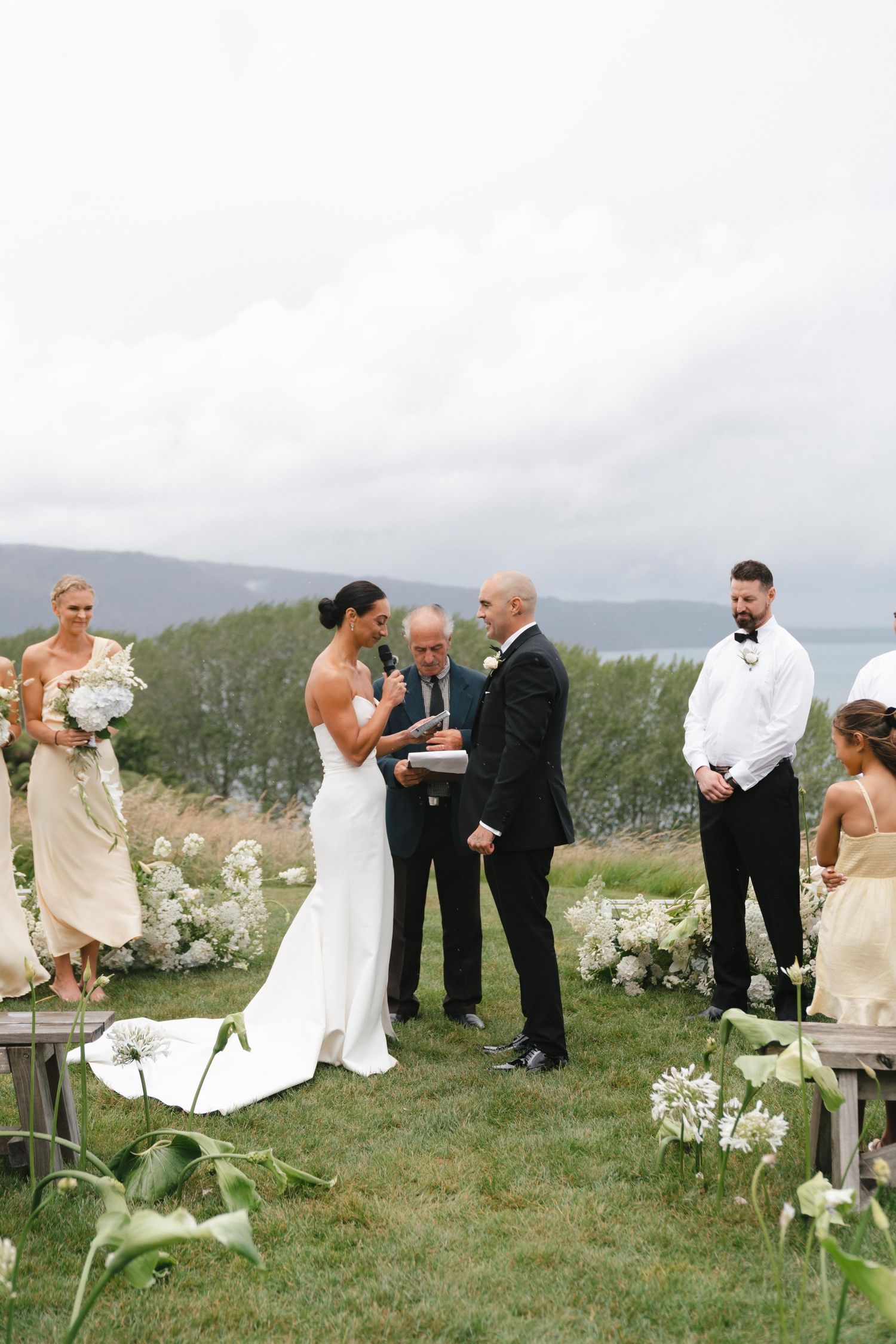 Wedding ceremony taking place on a hilltop overlooking mountains and water.