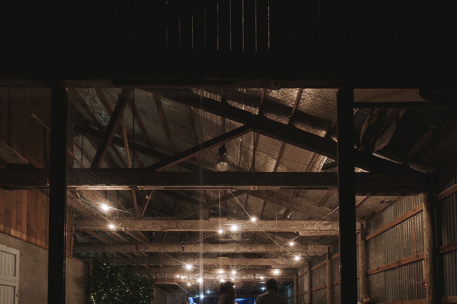Dark ceiling rafters with hanging lights in an industrial warehouse space creating a moody atmosphere.