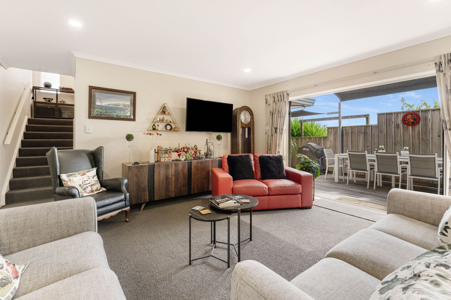 A modern open-concept living space with multiple rooms showcasing neutral decor, carpeted floors, and contemporary furniture.