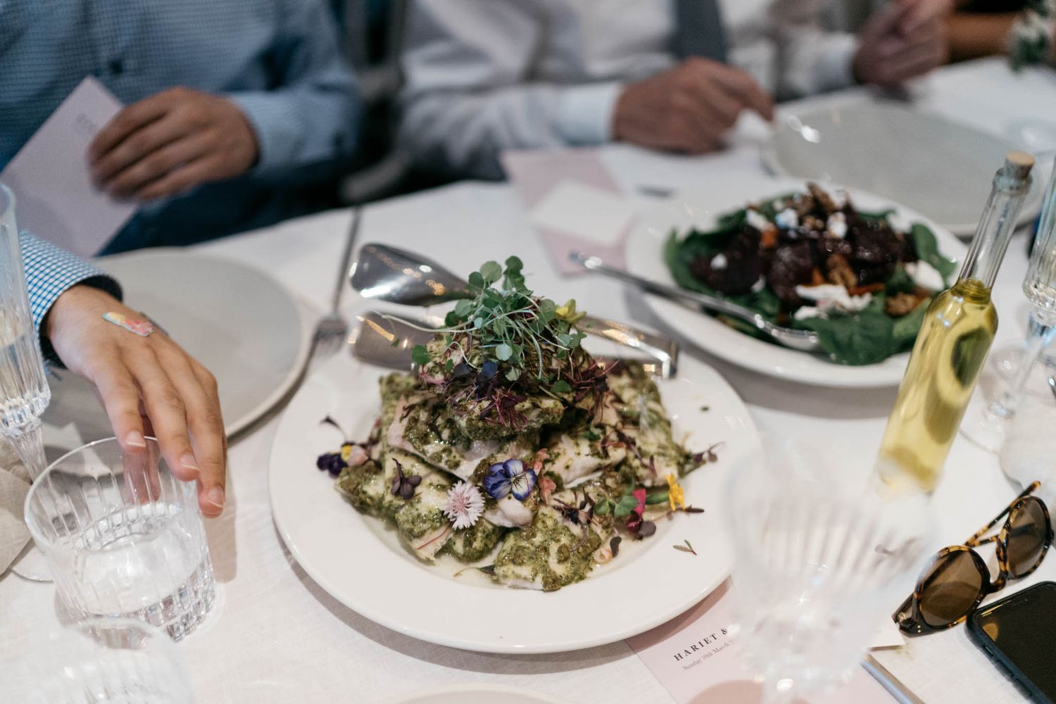 Fresh salad with mixed greens and microgreens served on white plates at an elegant dinner setting.
