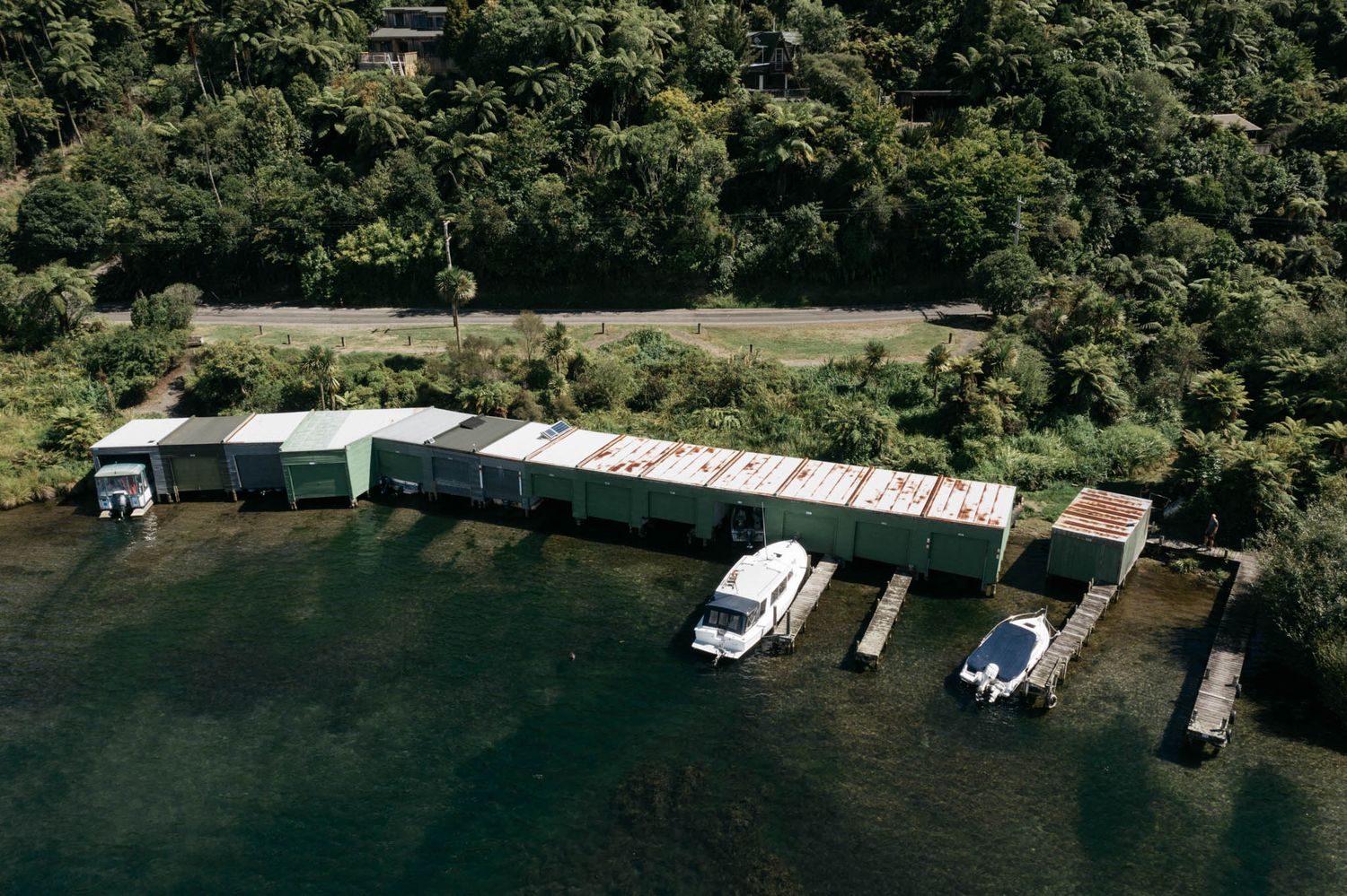 Aerial view of boat docks and small marina on a lake surrounded by lush green forest.