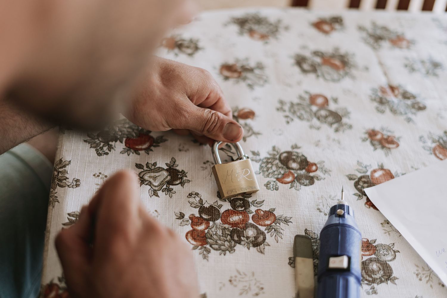 Someone solving a floral jigsaw puzzle with scattered pieces on a light wooden surface as seen from above.