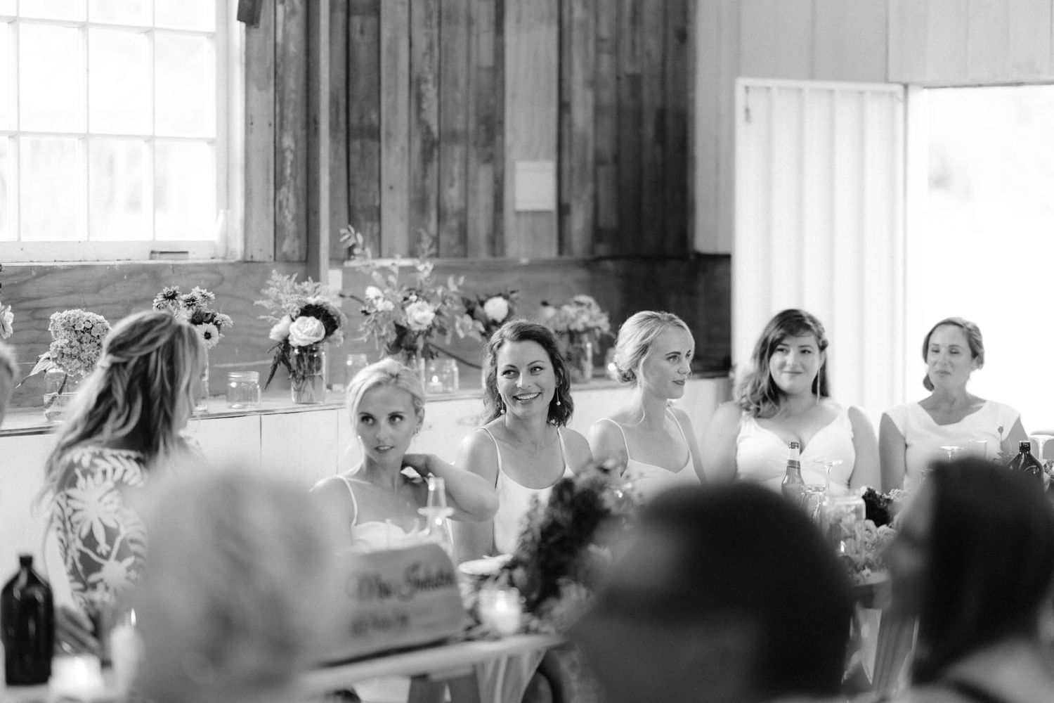 Black and white photo showing a group gathered at tables celebrating during what appears to be a wedding reception.