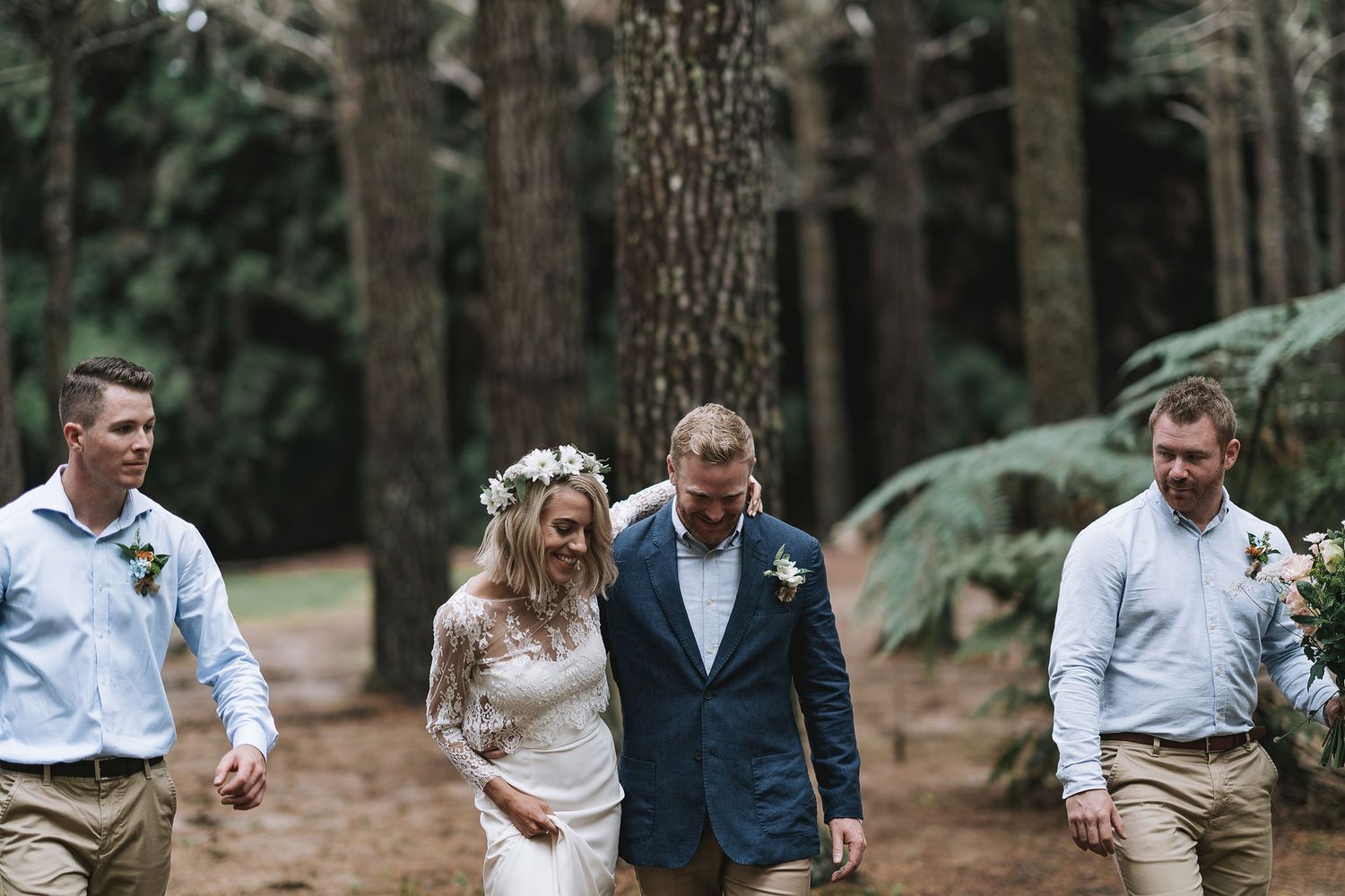 Wedding party walking together through a tall pine forest on a wedding day.