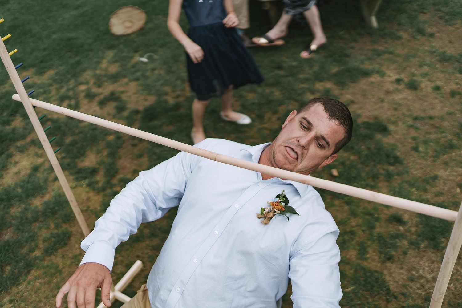 A group of people playing on a rope swing in a grassy outdoor setting during a fun summer gathering.