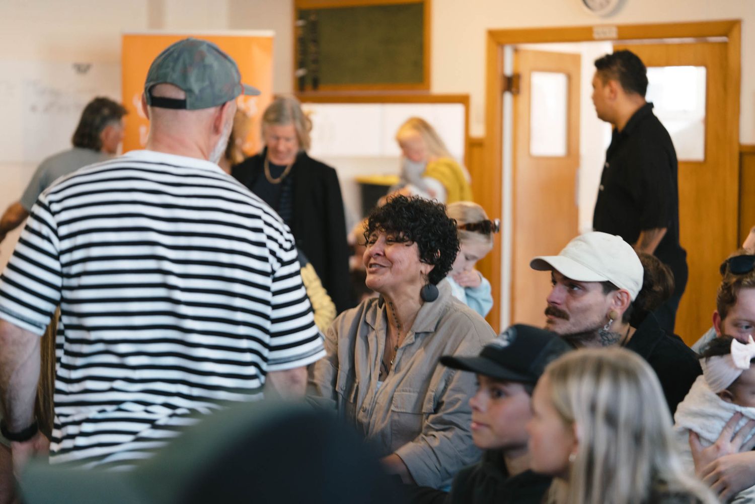 People engaged in conversation during a community gathering in a classroom setting.