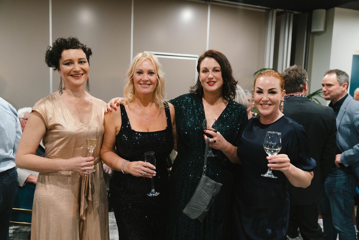 Group of friends in evening wear enjoying drinks at a formal event.