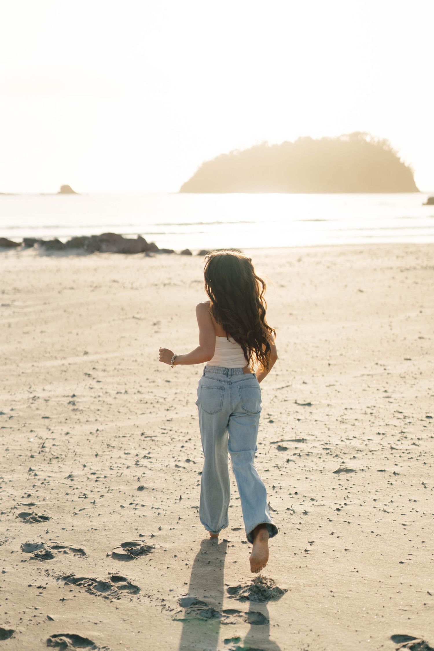 A series of three photos showing footprints in beach sand at sunset with someone walking.