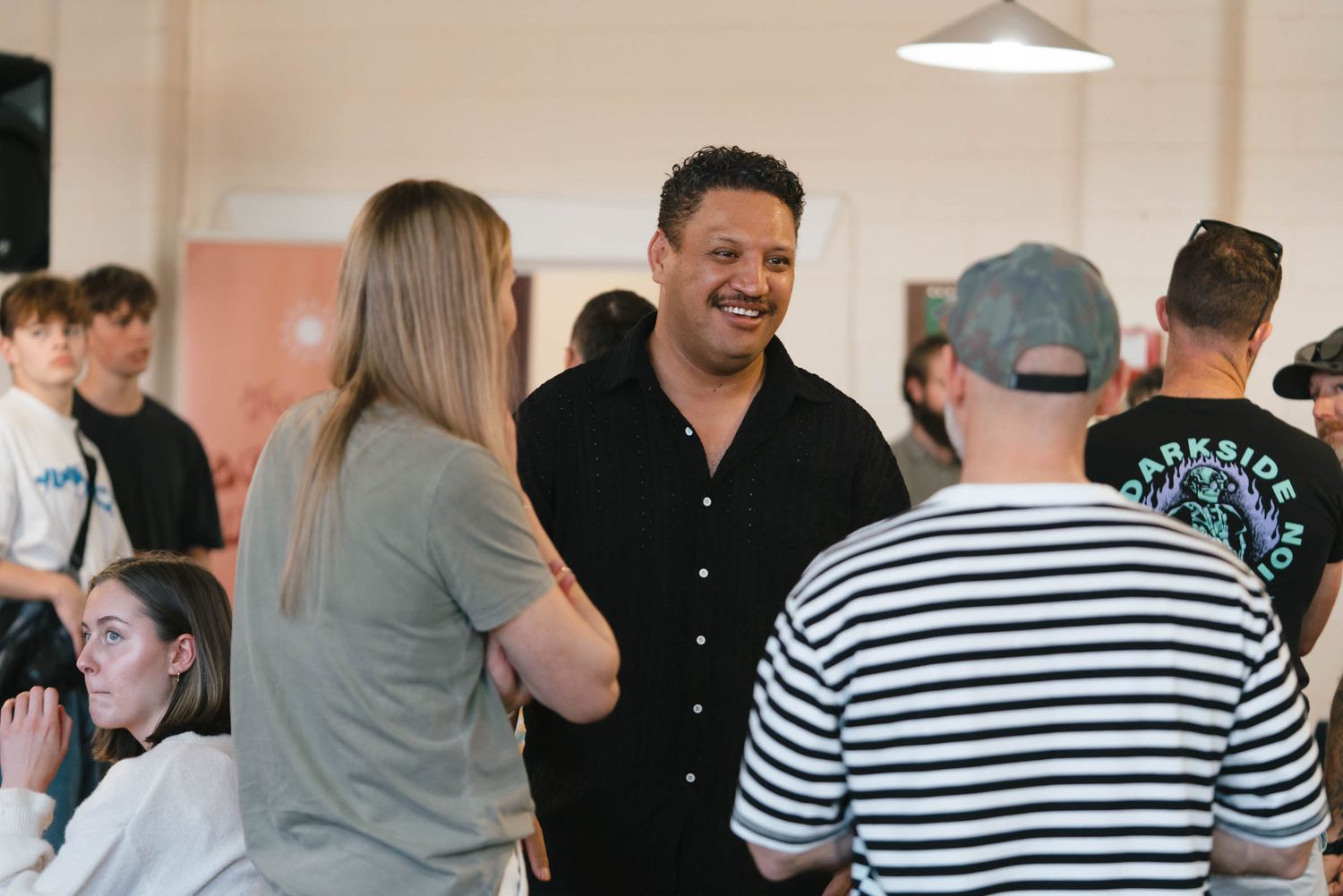 A group of people socializing and conversing in a bright indoor space.