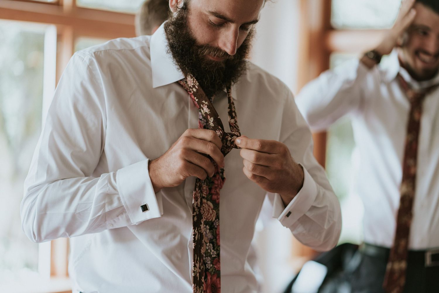 Person in a white dress shirt holds papers while surrounded by natural light in an elegant indoor setting.