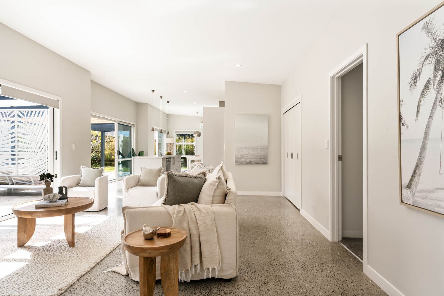 Modern white living room interior with beige sofas, natural light and elegant decor showcases an open concept design.