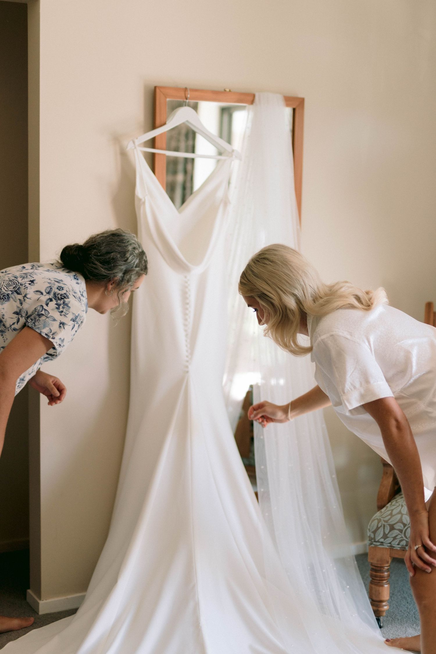 A wedding dress being carefully steamed and prepared before the ceremony in a home setting.