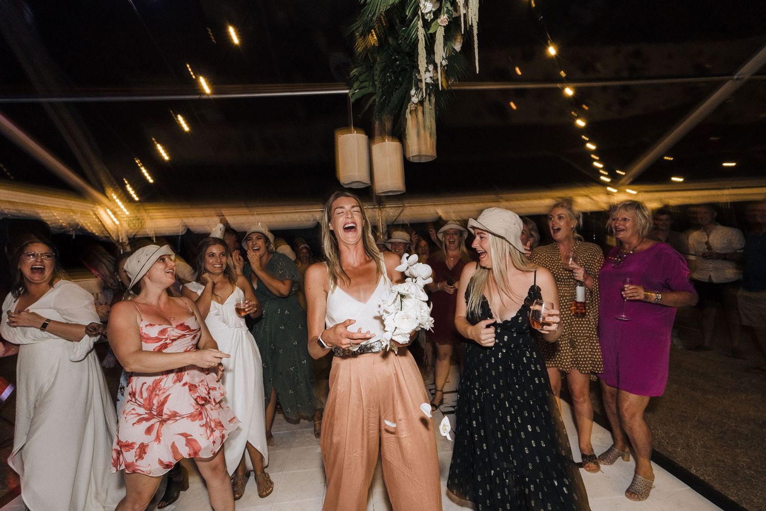 Evening celebration with guests dancing under warm lighting and decorative elements.