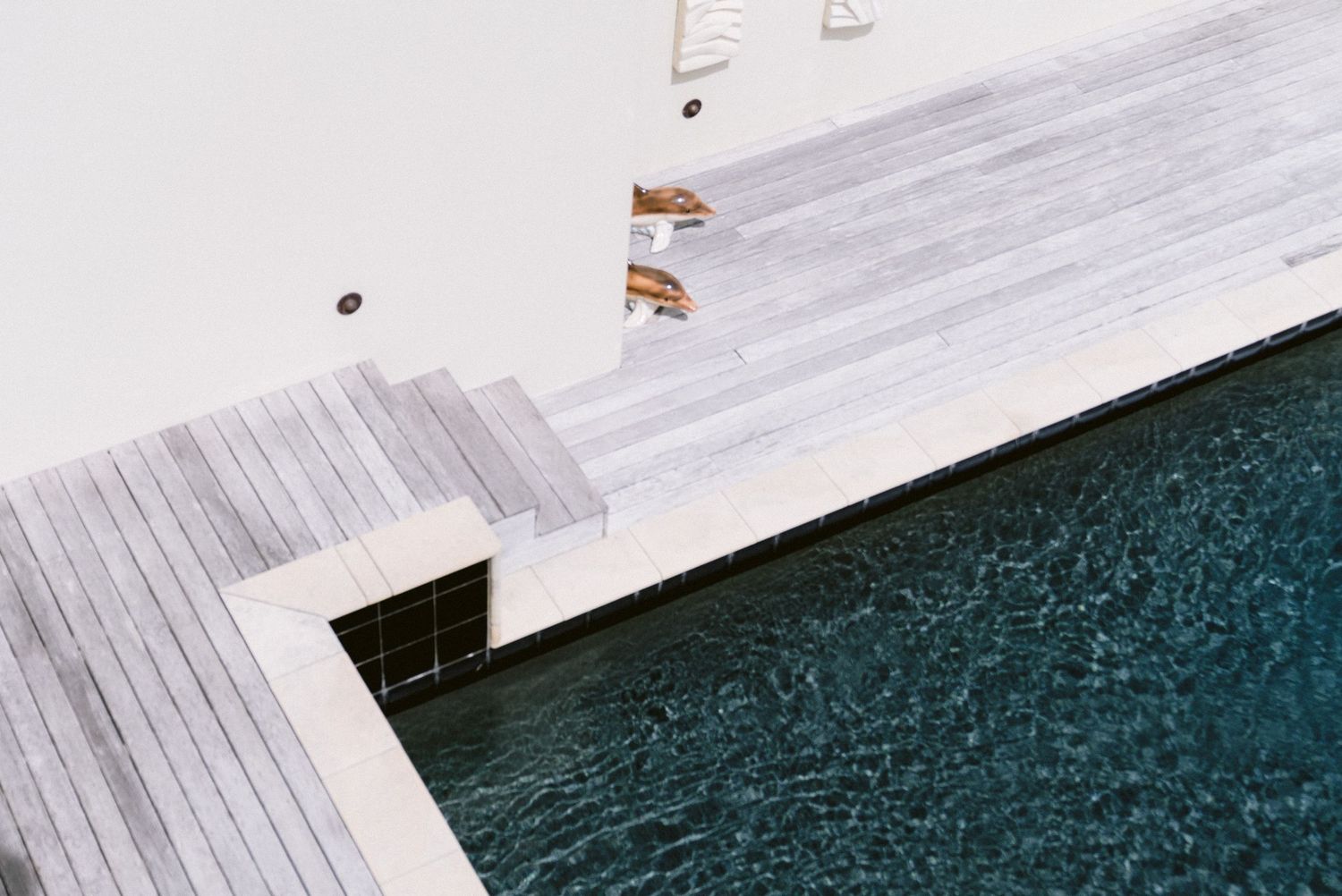 Modern wooden pier deck extending over dark blue water creating angular geometric lines and patterns.