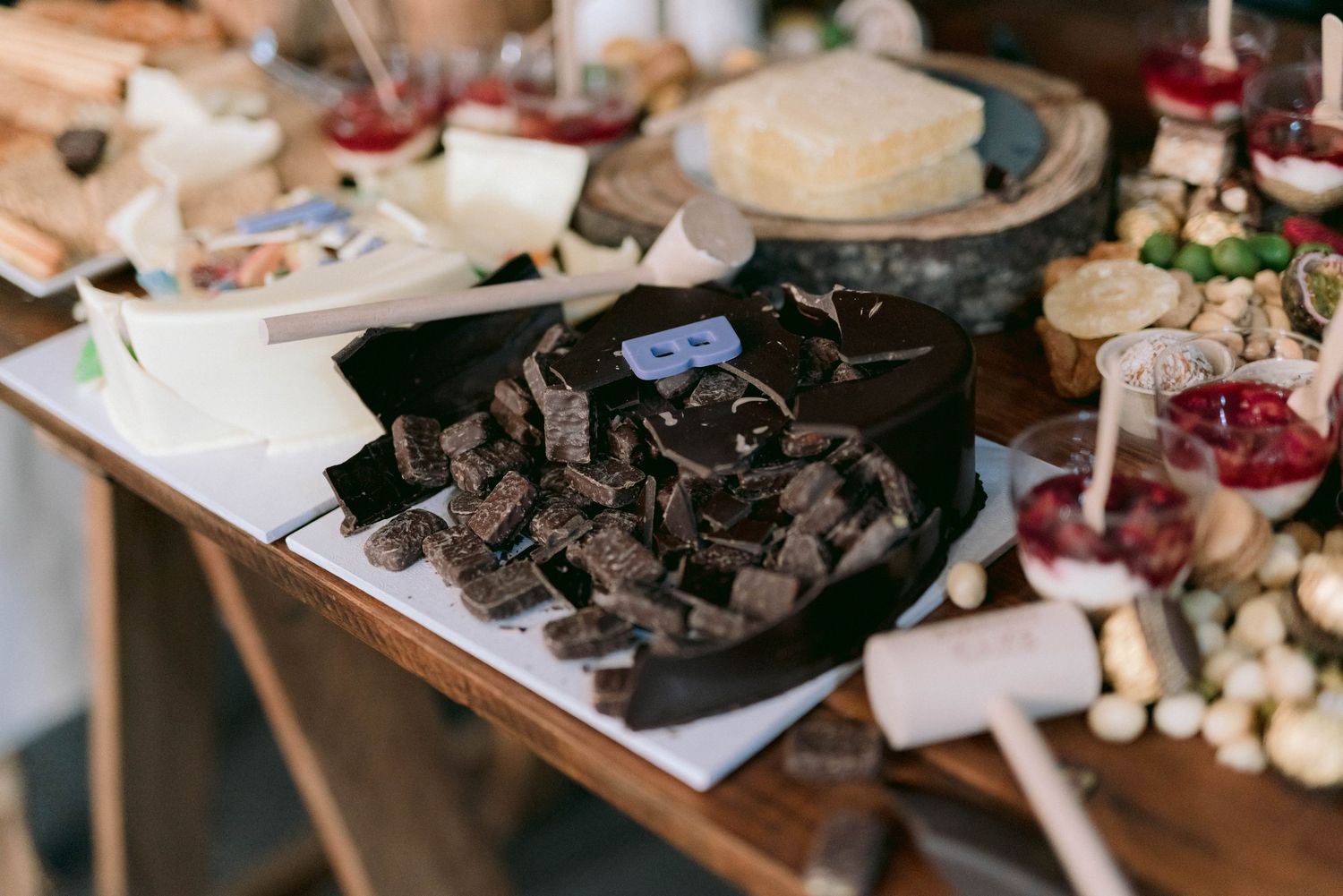 A rustic dessert table with chocolate treats and various wedding reception snacks displayed on wooden surfaces.
