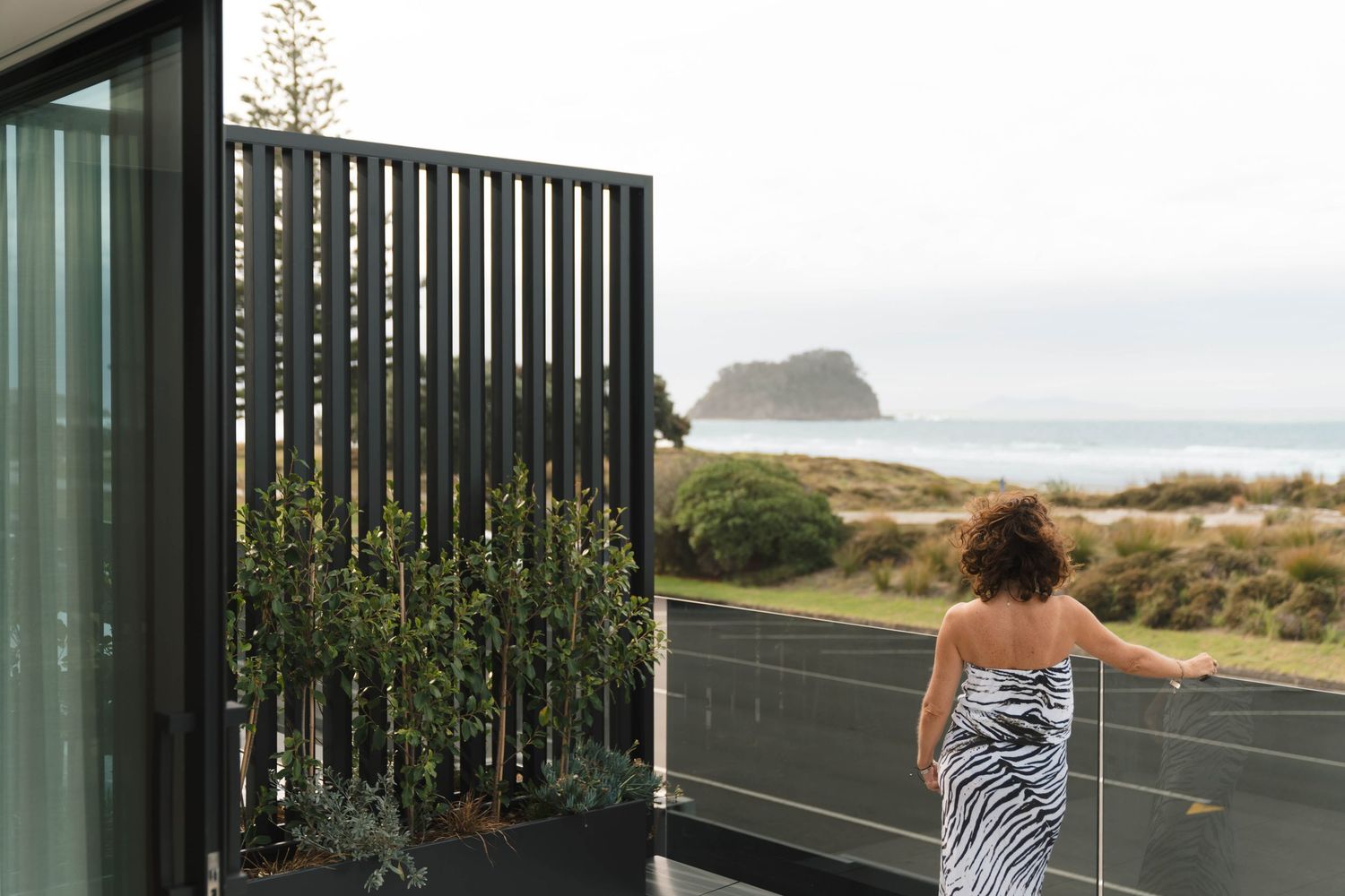 Beachfront deck with vertical black slat privacy screen overlooking ocean view.