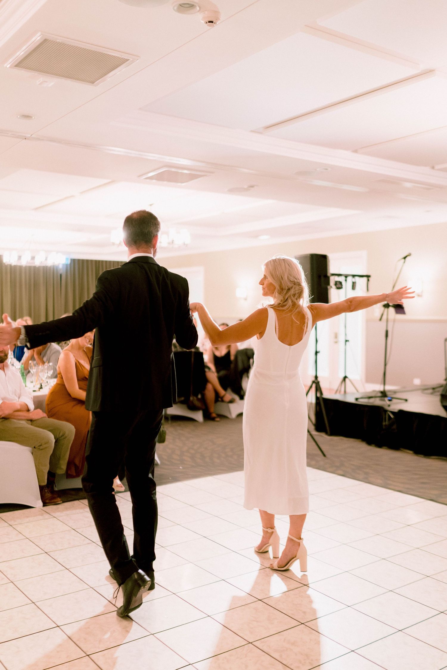 A couple dancing together on a tiled floor at an indoor wedding reception venue.