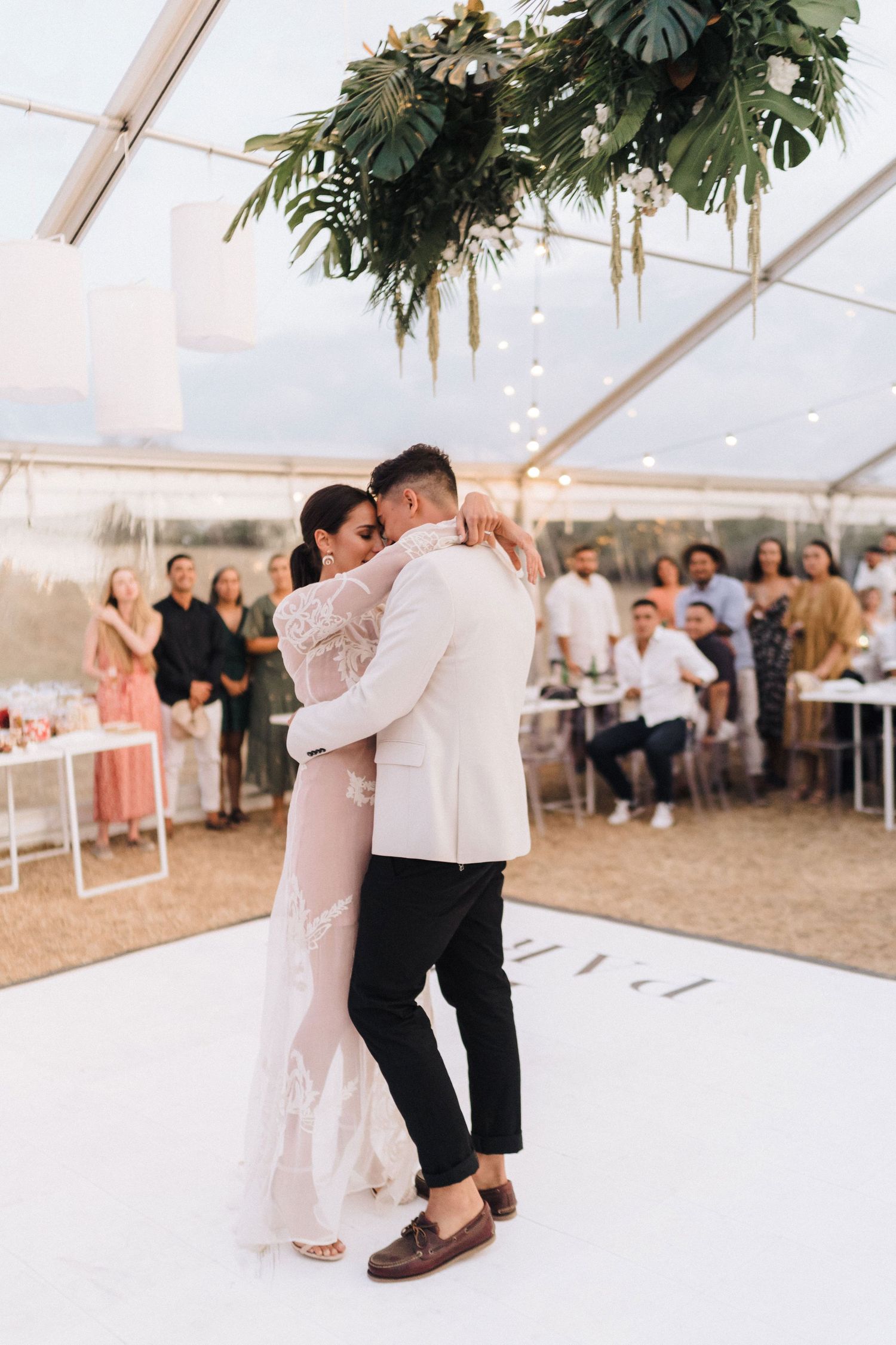 Couple shares their first dance under a botanical-decorated tent ceiling at an elegant wedding reception.