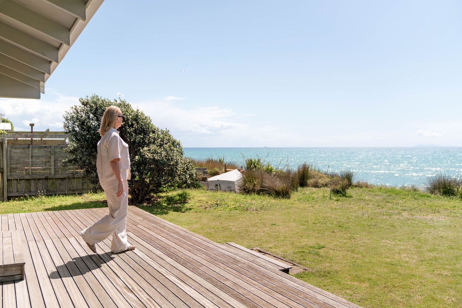 A wooden deck with ocean views features beachfront landscaping and natural coastal vegetation.