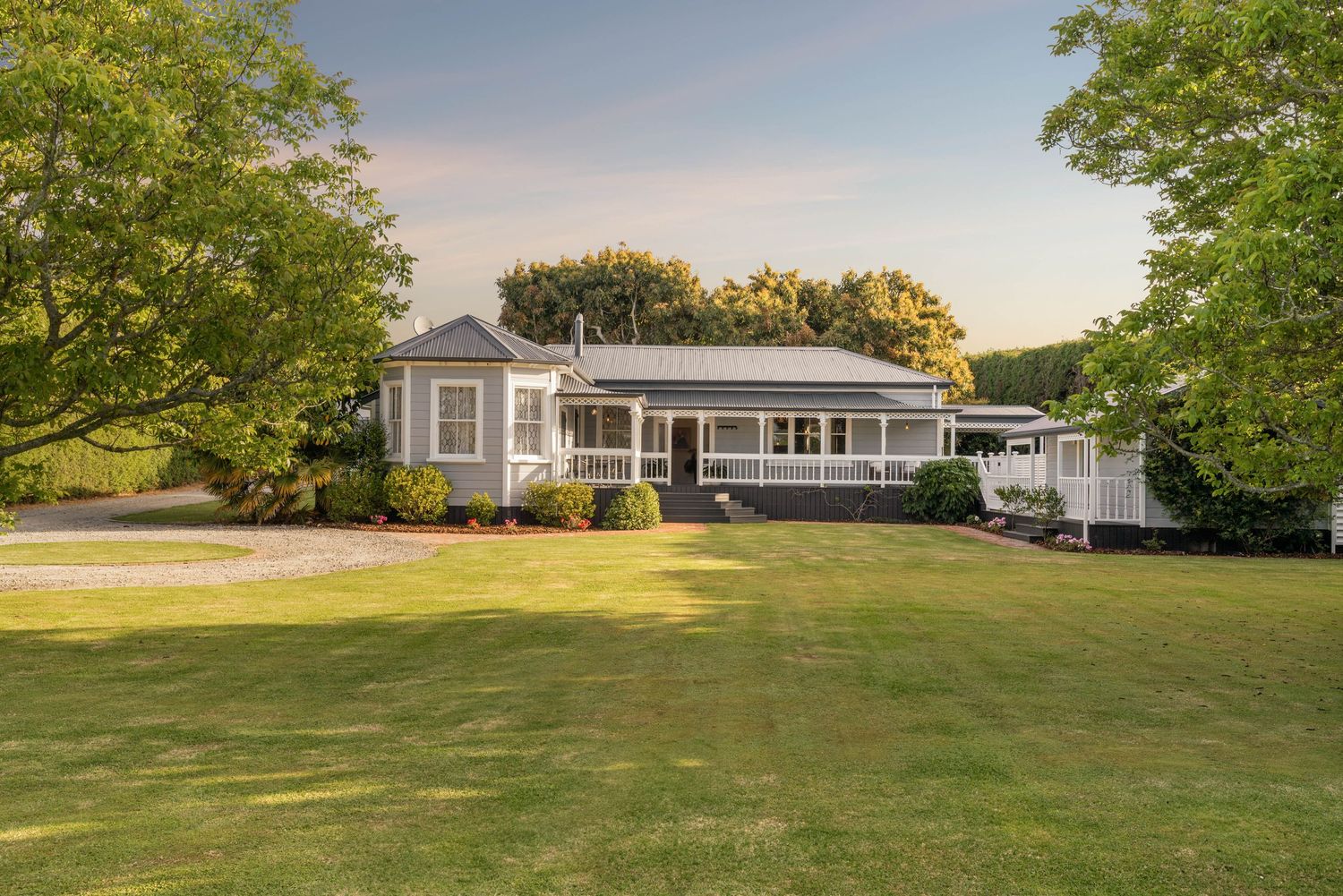 Large residential property with lush green lawns and mature trees viewed from above.