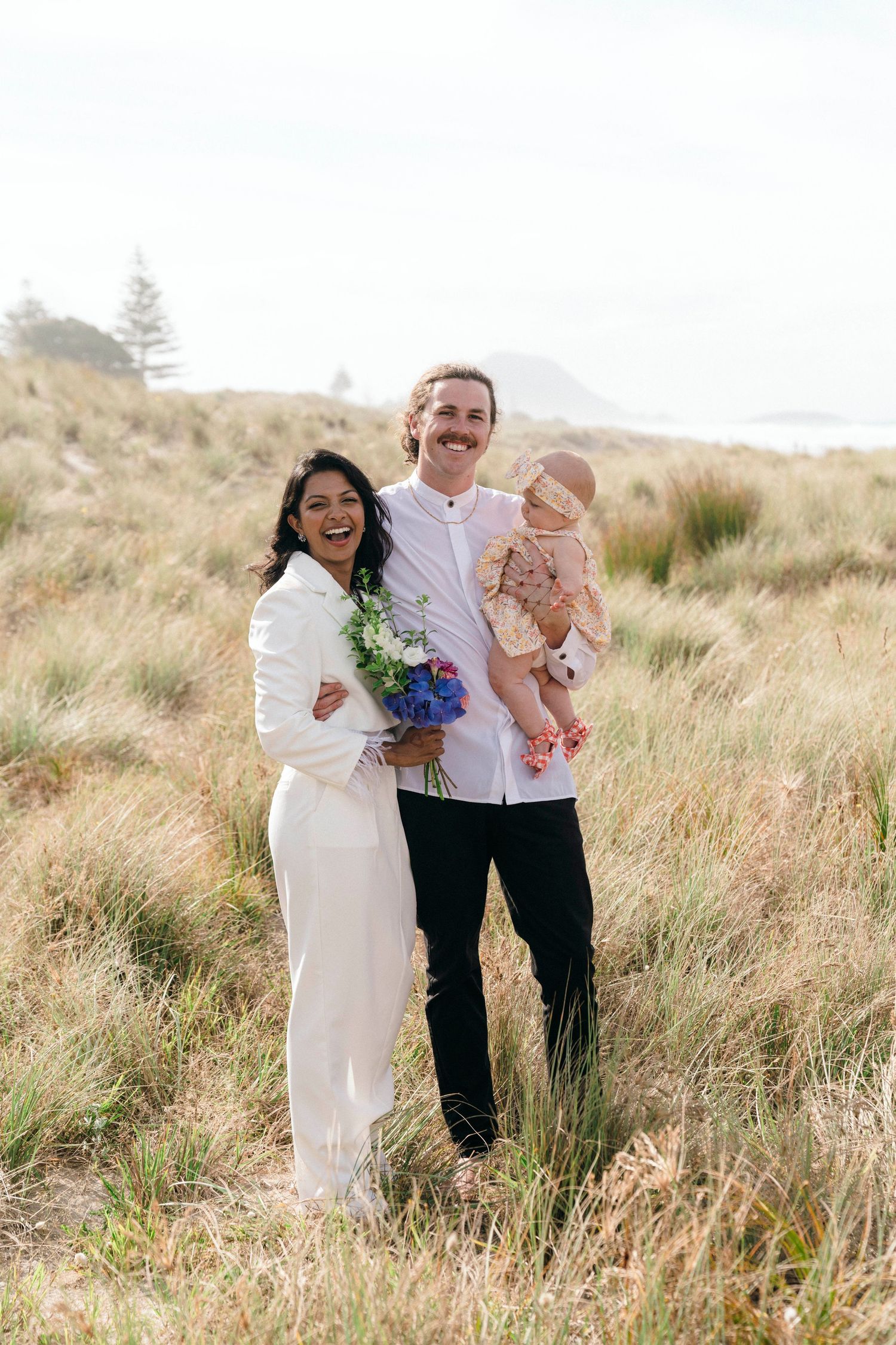 Happy family celebrates together in scenic coastal grasslands.