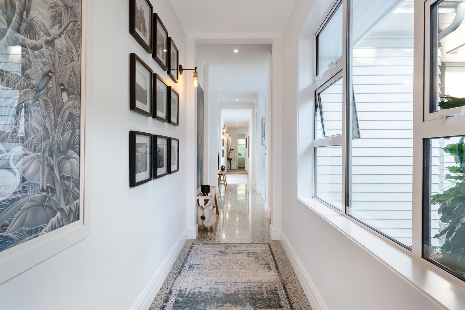Modern hallway with framed artwork gallery wall and large windows letting in natural light.