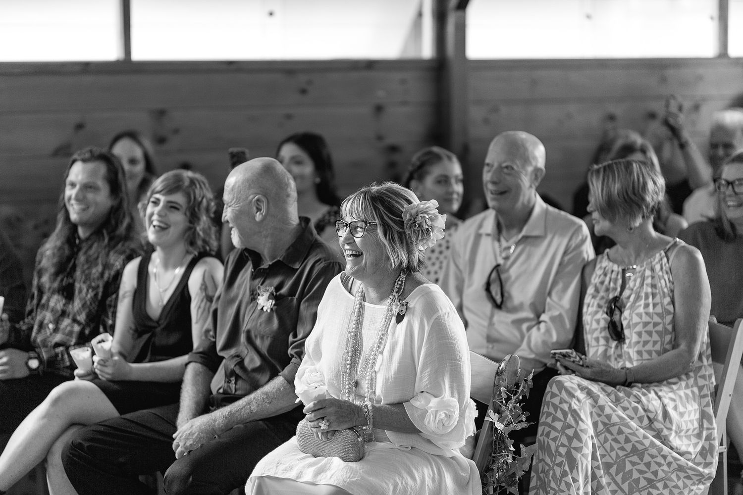 A black and white photograph shows wedding guests seated in rows at a ceremony watching attentively.