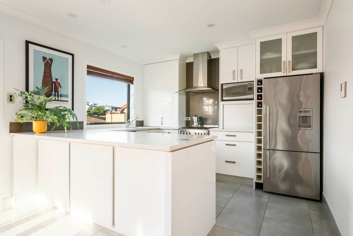 Bright white modern kitchen interior with stainless steel appliances and sleek cabinetry.